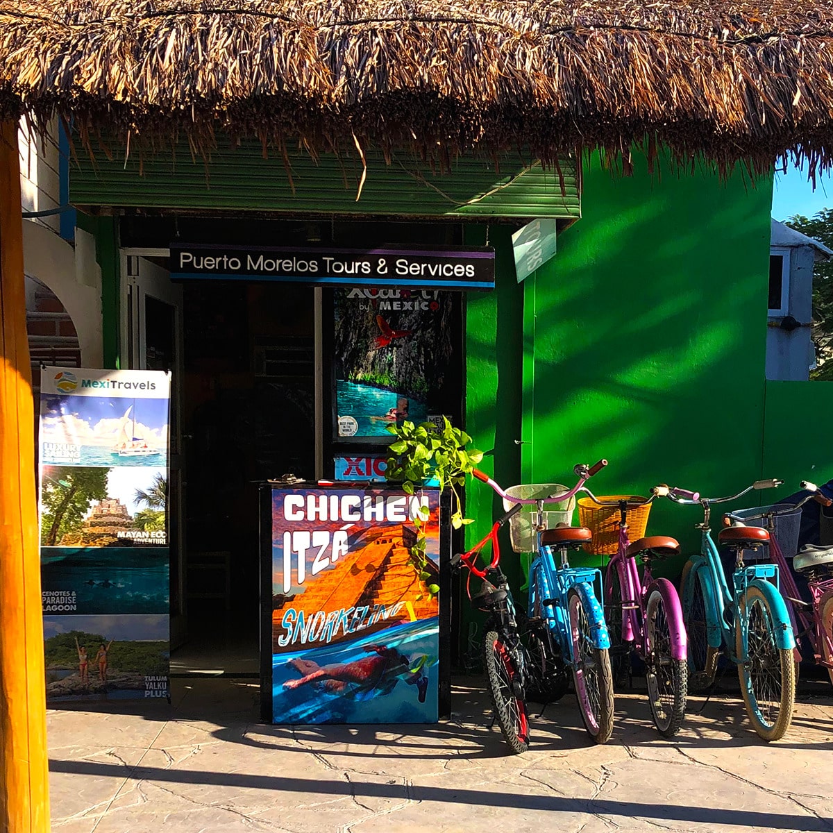 Colourful bicycles outside a green storefront in Puerto Morelos