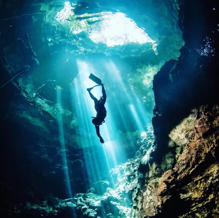 MExplor Freediving photography showing a diver silhouetted beneath beams of light