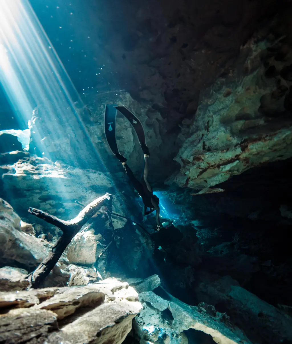 MExplor Freediver framed by underwater rock formations and natural light